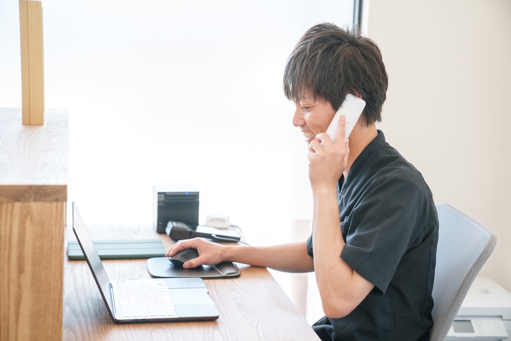 電話を受けながらパソコンを操作する施術者