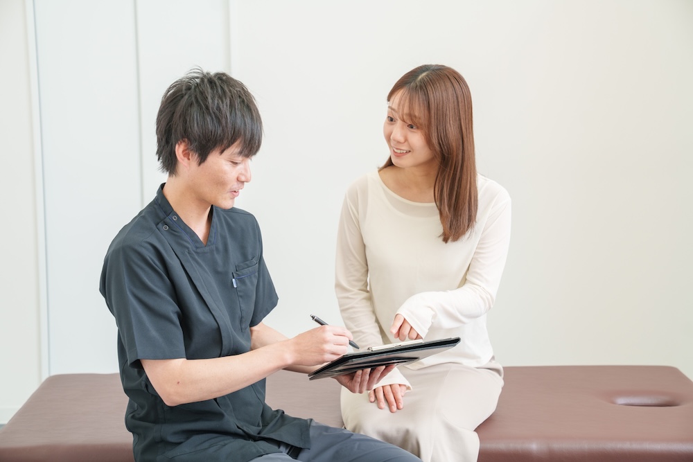 タブレットを手に問診する施術者と患者