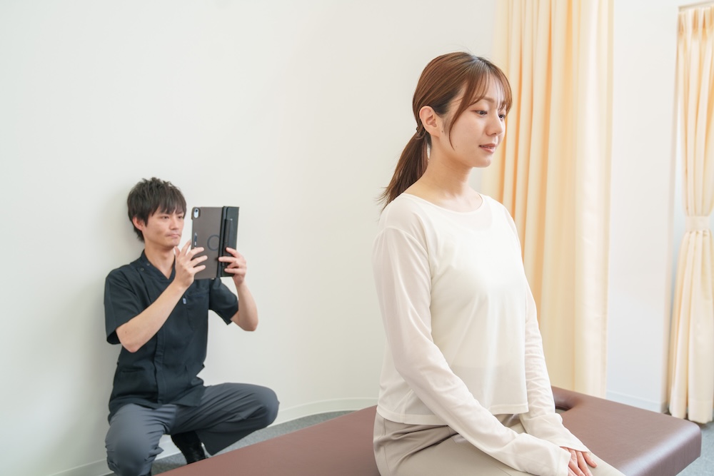 患者の首や腕の動きを確認する施術者