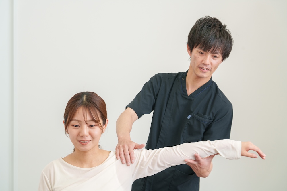 立位で腕や肩の状態を確認する施術者