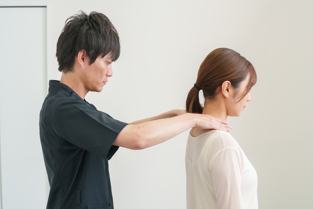 立位で首や肩の状態を確認する施術者
