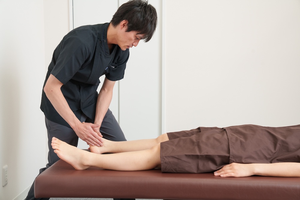 患者の脚を動かして確認する施術者