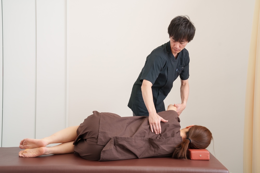 立位で脚や腰を整える施術者