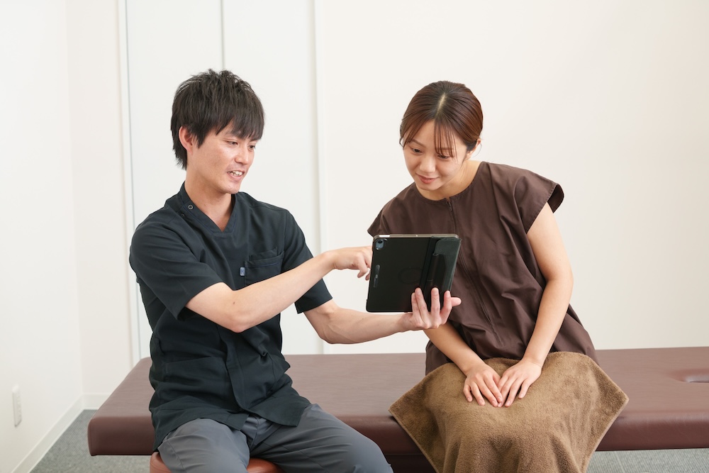 立位で身体の動きを確認する施術者と患者