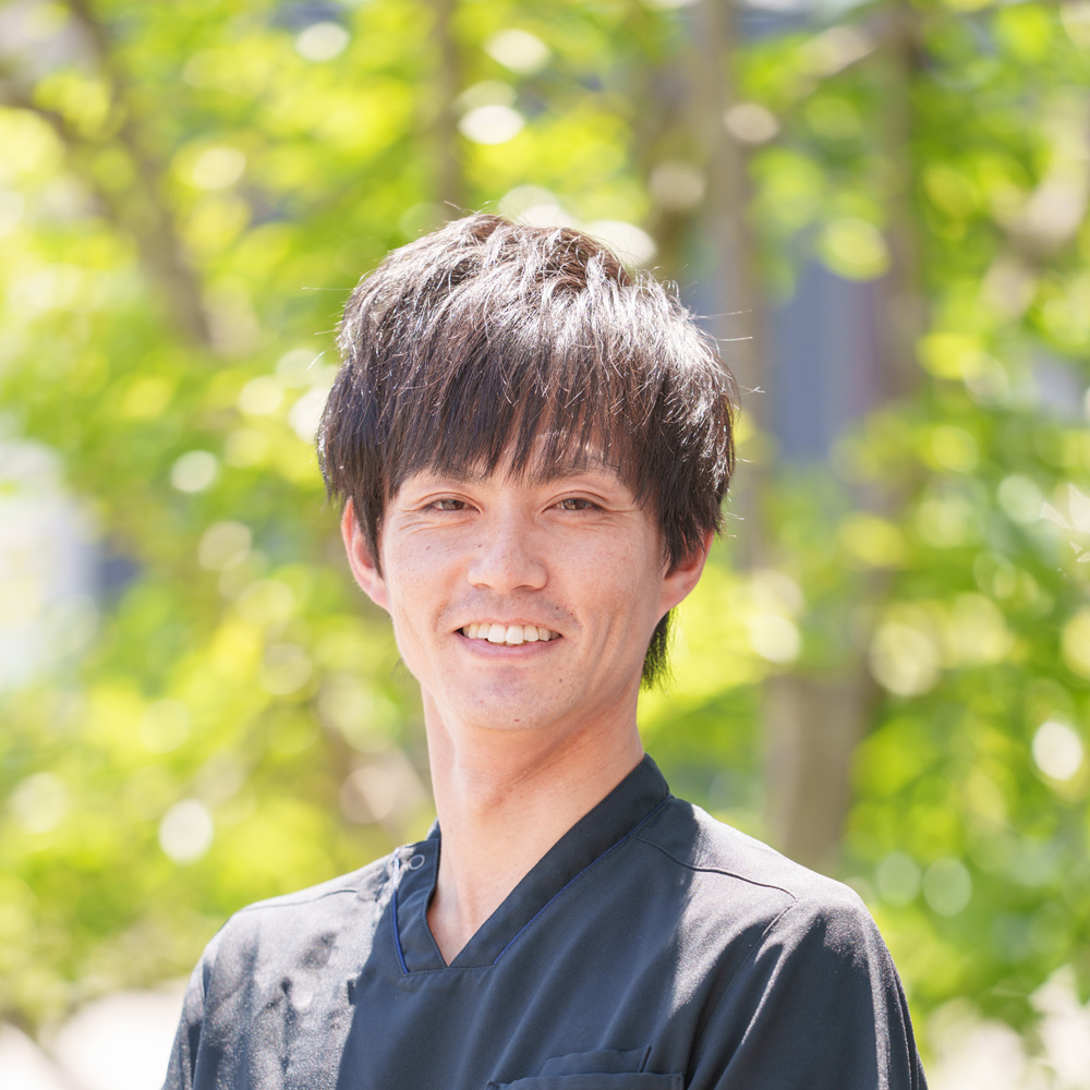 緑の木々の前で微笑む院長境田涼平